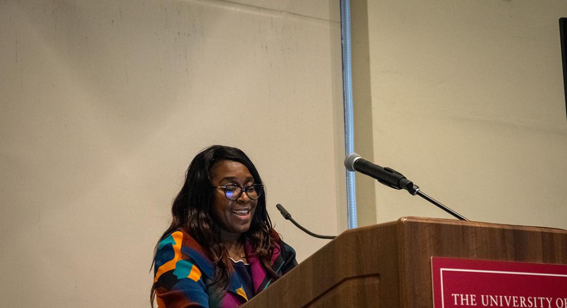 Patricia Posey standing in front of a UChicago podium speaking.