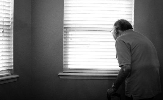 an elderly man looking out of a window