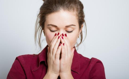 woman with hands over her nose and mouth