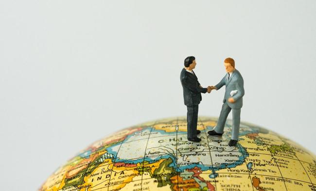 Two miniature figures shaking hands over China