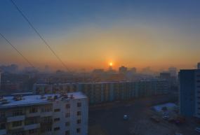 sun rising over hazy cityscape