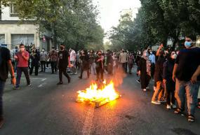 Protestors gather around a fire on the street in Tehran