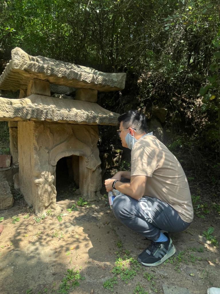 Professor Lin kneeling next to artifact